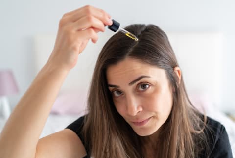 Woman Applying Hair Serum To Her Hair